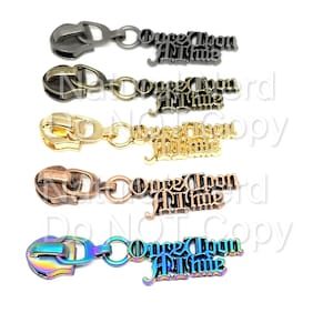 May include: Five zipper pulls with the words "Once Upon A Time" in a gothic font. The zipper pulls are in different colors: black, gold, copper, bronze, and rainbow.
