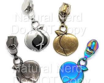 May include: Three zipper pulls with peach charms. The charms are silver, gold, and iridescent blue.