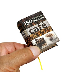 May include: A small, brown book with a yellow ribbon bookmark. The cover features a photo of coffee beans and a cup of coffee with the text "150 maneras de disfrutarlo cafe".