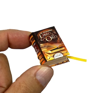 May include: A miniature book with a gold and brown cover. The title of the book is "El Pequeno Libro de Oro".