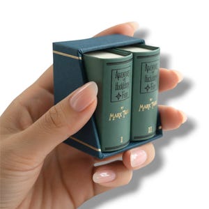 May include: A miniature set of "Adventures of Huckleberry Finn" books in a teal blue case. The two small green books are labeled "I" and "II" with gold lettering. The case has gold trim.