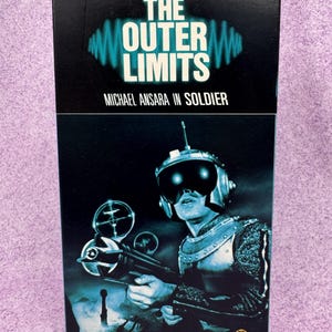 May include: A VHS tape case for The Outer Limits episode Soldier starring Michael Ansara. The cover features a dark blue and black graphic of a futuristic soldier in a helmet and armor holding a weapon, with the text Do not attempt to adjust the picture. We are controlling transmission.