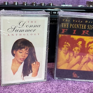 May include: Two cassette tapes, one with a photo of Donna Summer and the text "The Donna Summer Anthology", and the other with a photo of The Pointer Sisters and the text "The Very Best Of The Pointer Sisters FIRE".
