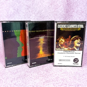 May include: Three vintage cassette tapes featuring album art. One tape has a green and orange design, another shows a sunset, and the third displays the band Creedence Clearwater Revival with the text "Chronicle".