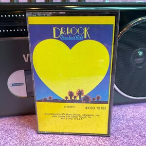 Puede incluir: Una cinta de casete amarilla con una forma de corazón en la parte delantera. La cinta se titula "Dr. Hook Greatest Hits" y tiene los números de catálogo "C 153513" y "4XOO 12122". La cinta está fabricada por RCA Music Service, Indianápolis, Ind. bajo licencia de Capitol Records, Inc. "Mfd. & Prtd. in U.S.A."
