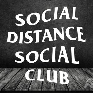 May include: Black and white text on a dark gray background reads "SOCIAL DISTANCE SOCIAL CLUB". A wooden floor is in the foreground.