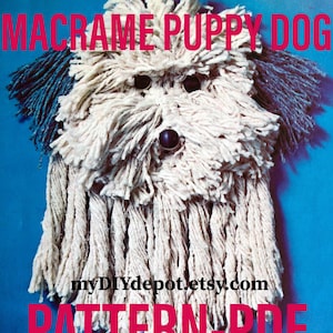 May include: A macrame puppy dog pattern. The dog is made of cream-coloured macrame cord with dark blue accents for the ears. The dog has black button eyes and a black button nose. The text "MACRAME PUPPY DOG" and "PATTERN-PDF" are in pink.