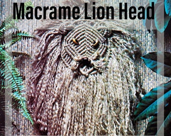May include: Macrame lion head wall hanging pattern. The pattern is available as a PDF download. The lion head is made with brown yarn and has a textured look. The lion has a black nose and yellow eyes.