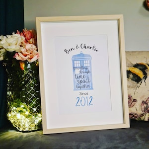 Peut inclure: Une impression encadrée avec une illustration aquarelle d'une boîte de police bleue, le texte "Ben & Charlie voyageant à travers le temps et l'espace ensemble Depuis 2012" et un cœur bleu.