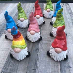 May include: A collection of ten hand-painted ceramic gnomes with various colors and designs. The gnomes have white beards and black shoes.