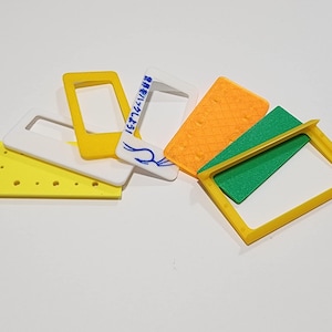 May include: An assortment of colorful, geometric shapes in yellow, white, orange, and green. Some shapes are rectangular frames, while others are solid blocks. One white frame has blue text and a drawing.