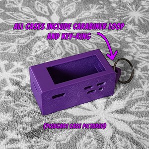 Pode incluir: Estojo roxo com um chaveiro e um mosquet&atilde;o. O estojo tem recortes para bot&otilde;es e portas.  "ALL CASES INCLUDE CARABINER LOOP AND KEY-RING" e "(PISUGAR1 CASE PICTURED)" est&atilde;o escritos na imagem.