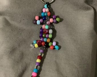 May include: A colorful beaded lizard keychain with a silver key ring. The lizard is made of small, colorful beads and has a long tail.