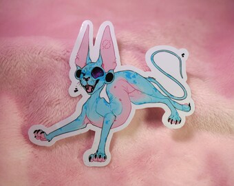 May include: A blue and pink sticker of a cartoon sphynx cat with large ears and a mischievous expression. The cat has a black eye and a black nose.