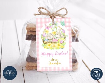 Peut inclure: Etiquette cadeau en vichy rose et blanc avec une illustration aquarelle de deux lapins dans un panier avec des œufs de Pâques. L'étiquette indique "Joyeuses Pâques ! Avec amour, Jennifer".