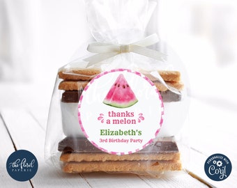 Puede incluir: Una bolsa transparente de celofán atada con una cinta blanca, que contiene galletas y una pegatina redonda. La pegatina presenta una rodaja de sandía en acuarela y el texto "thanks a melon" y "Elizabeth's 3rd Birthday Party".