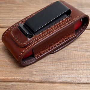 May include: A white ceramic mug with a black handle and the text "But First, Coffee" in a bold, black font. The mug is set against a blurred background, suggesting a cozy setting.