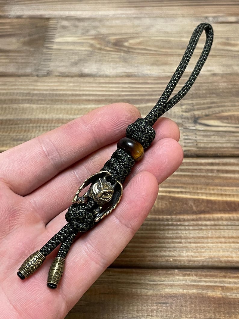 May include: A green paracord keychain with a brass owl charm and a tiger's eye bead.