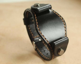 May include: Black leather watch strap with orange stitching and a metal buckle.
