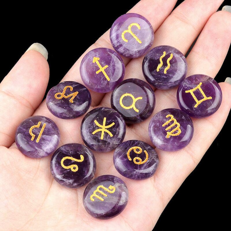 May include: Set of 12 amethyst gemstone zodiac signs with gold lettering. Each stone is a different zodiac sign, including Aries, Taurus, Gemini, Cancer, Leo, Virgo, Libra, Scorpio, Sagittarius, Capricorn, Aquarius, and Pisces.