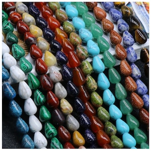 May include: A variety of gemstone beads in teardrop shapes, including turquoise, green, red, brown, white, and blue. The beads are strung together on a string and are ready to be used for jewelry making.