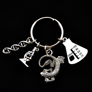 May include: Silver keychain with a DNA double helix, a microscope, a lizard charm, and a beaker charm with a 100 ml measurement.