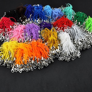 May include: A large assortment of colorful string cords with silver metal clasps. The cords are bundled together in various colors, including red, blue, green, yellow, orange, purple, pink, white, and black.