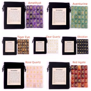 May include: A collection of rune sets in various gemstones, including amethyst, aventurine, tiger eye, clear quartz, obsidian, rose quartz, and red agate. Each set is displayed with a black drawstring bag and a card with the word "Divination".