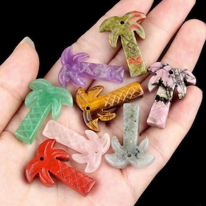 Op de afbeelding: Assortiment van acht palmboomvormige edelsteen hangers. De hangers zijn gemaakt van verschillende stenen, waaronder amethist, groene aventurijn, tijgeroog, rozenkwarts, labradoriet en roze rhodonite.