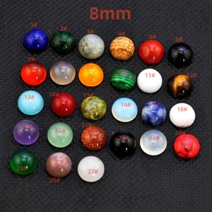 May include: Assortment of 27 different 8mm round cabochon gemstones. The gemstones are arranged in rows and numbered 1 through 27. The gemstones are various colors, including red, green, blue, purple, orange, brown, white, and black.