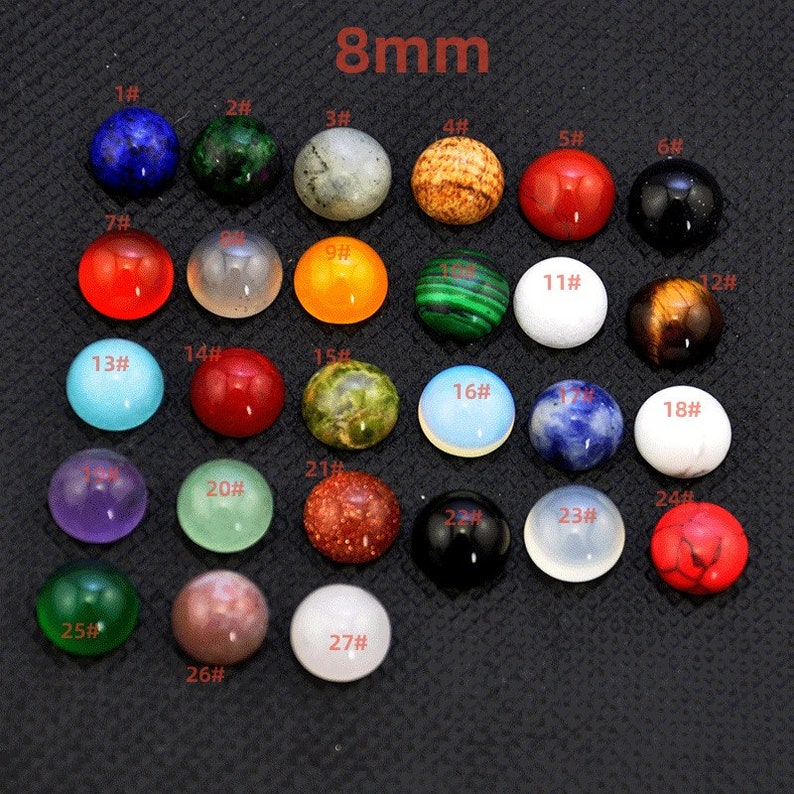 May include: Assortment of 27 different 8mm round cabochon gemstones. The gemstones are arranged in rows and numbered 1 through 27. The gemstones are various colors, including red, green, blue, purple, orange, brown, white, and black.