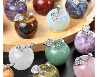 May include: Assortment of crystal apple ornaments in various colors and styles, including amethyst, tiger's eye, green aventurine, rose quartz, and opal. Each apple features a silver metal stem and leaf with rhinestones.