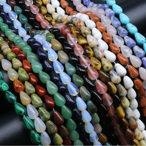 May include: A variety of gemstone beads in teardrop shapes, including green, blue, red, brown, and white. The beads are strung together on a string and are ready to be used for jewelry making.
