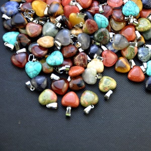 Puede incluir: Un gran surtido de colgantes de piedras preciosas en forma de coraz&oacute;n en varios colores, incluyendo rojo, verde, azul, marr&oacute;n y amarillo. Los colgantes est&aacute;n hechos de piedras naturales y tienen lazos de metal plateado.