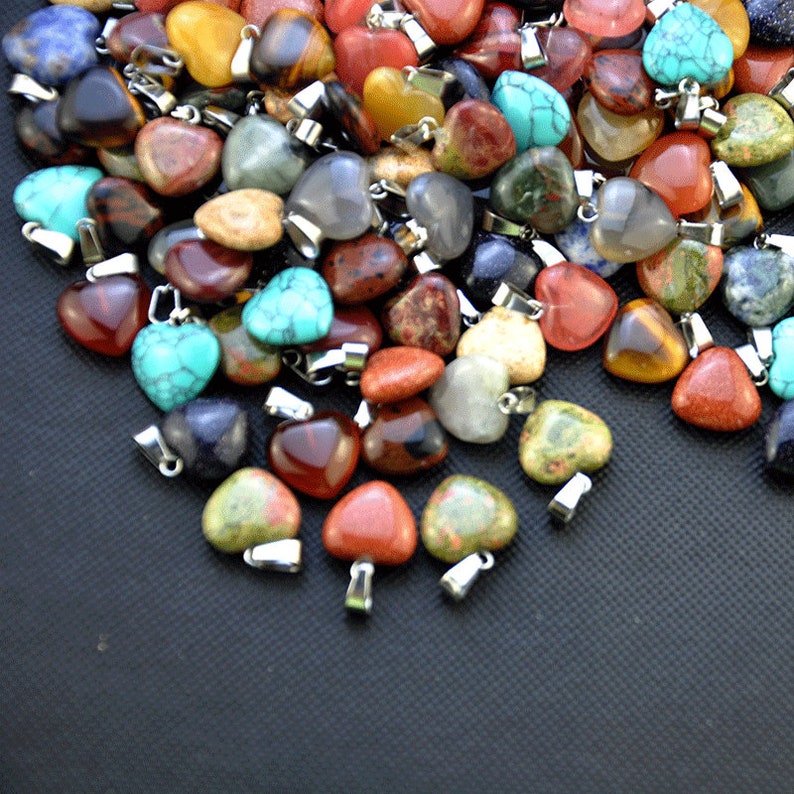 Puede incluir: Un gran surtido de colgantes de piedras preciosas en forma de coraz&oacute;n en varios colores, incluyendo rojo, verde, azul, marr&oacute;n y amarillo. Los colgantes est&aacute;n hechos de piedras naturales y tienen lazos de metal plateado.