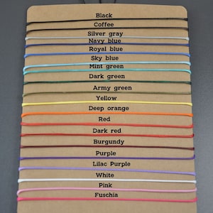 May include: A color chart with 18 different colored cords, each with a label indicating its color. The colors include black, coffee, silver gray, navy blue, royal blue, sky blue, mint green, dark green, army green, yellow, deep orange, red, dark red, burgundy, purple, lilac purple, white, pink, and fuchsia.