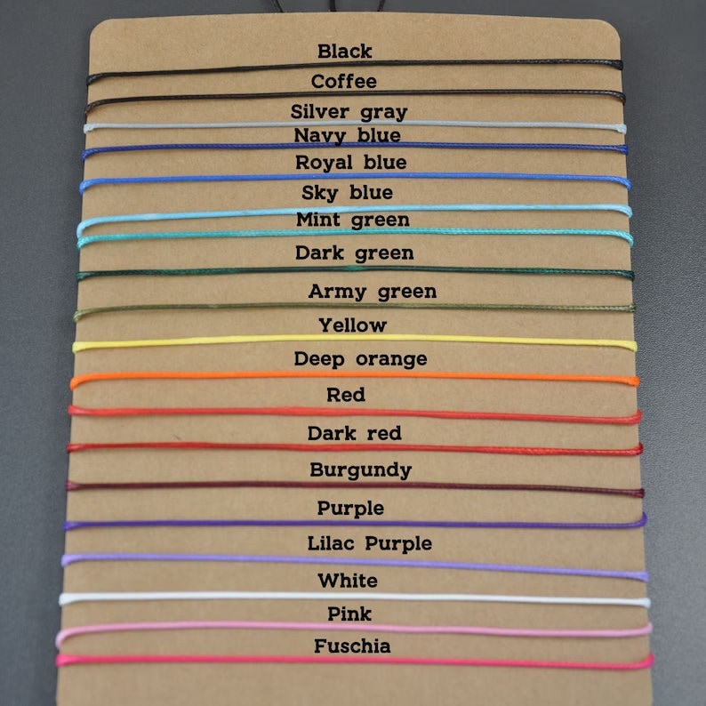 May include: A color chart with 18 different colored cords, each with a label indicating its color. The colors include black, coffee, silver gray, navy blue, royal blue, sky blue, mint green, dark green, army green, yellow, deep orange, red, dark red, burgundy, purple, lilac purple, white, pink, and fuchsia.