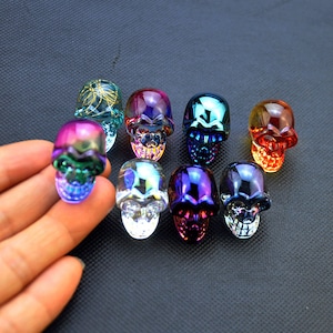 Può includere: Otto figurine di teschio in vetro iridescente in vari colori, tra cui viola, blu, verde, rosso, oro e nero.