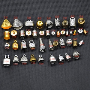 May include: Assortment of silver and gold metal pendant charms with various designs. The charms are numbered 1 through 42.