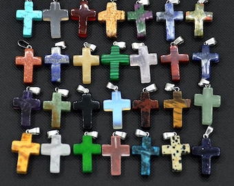 May include: A selection of gemstone cross pendants in a variety of colours, such as turquoise, grey, red, gold, green, purple, blue, and black. Each cross has a silver-tone bail for attaching to a chain. The crosses are made of different types of stone.