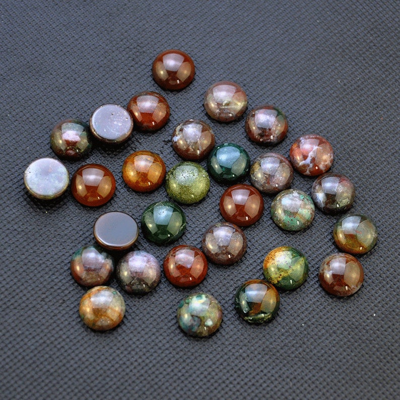 May include: A collection of 25 round, multi-colored agate cabochons. The cabochons are approximately 1 inch in diameter and feature a variety of colors, including brown, green, red, and white.