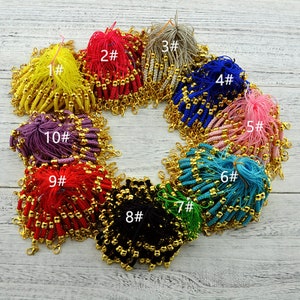 Puede incluir: Surtido de llaveros de cuerda de colores con cuentas doradas y cierres. Los llaveros están dispuestos en círculo sobre una superficie de madera. Los números del 1 al 10 están escritos en los llaveros.