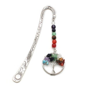 May include: A silver metal bookmark with a sun design and a dangling charm. The charm features a wire tree with colorful gemstones and a strand of beads in various colors. The bookmark is designed for use in books.