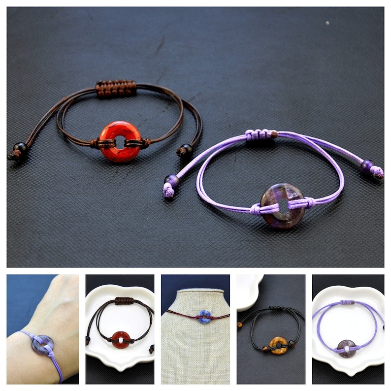 May include: Two adjustable bracelets with a round charm. One bracelet has a red charm and brown cord. The other bracelet has a purple charm and a purple cord.