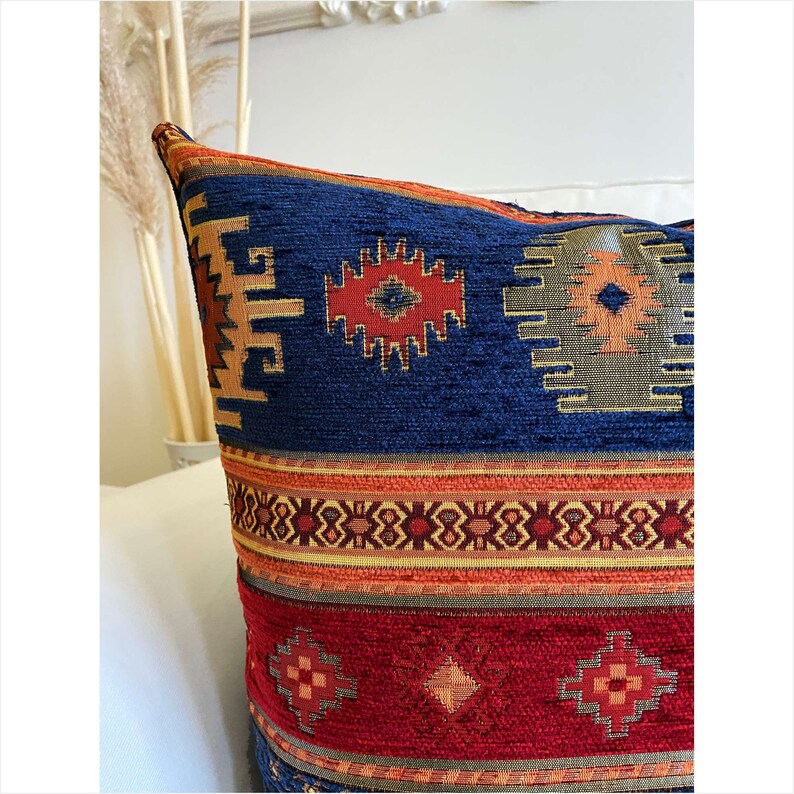 May include: A blue, red, and orange patterned throw pillow with a geometric design. The pillow has a woven texture and is made of a soft, comfortable fabric.
