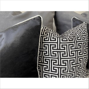 May include: Two decorative throw pillows with a black and white geometric pattern. One pillow is black velvet with a white trim. The other pillow has a white trim and a black and white geometric pattern.