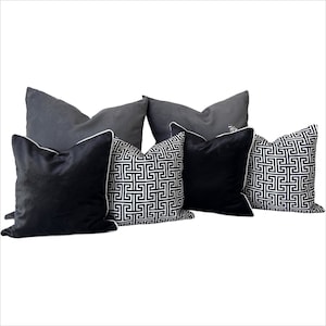 May include: A set of five decorative throw pillows. Two pillows are black velvet with white piping. Three pillows are black and white geometric patterned with white piping.