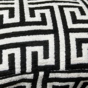 May include: Black and white geometric pattern on a fabric surface. The pattern is a repeating design of interlocking squares and rectangles.