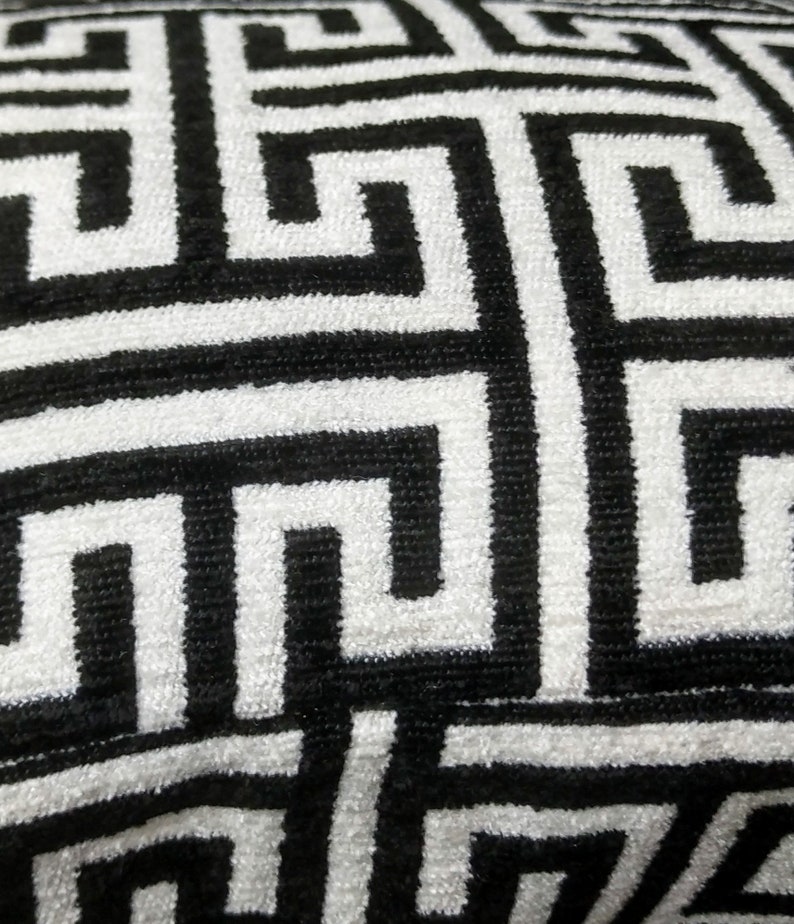 May include: Black and white geometric pattern on a fabric surface. The pattern is a repeating design of interlocking squares and rectangles.