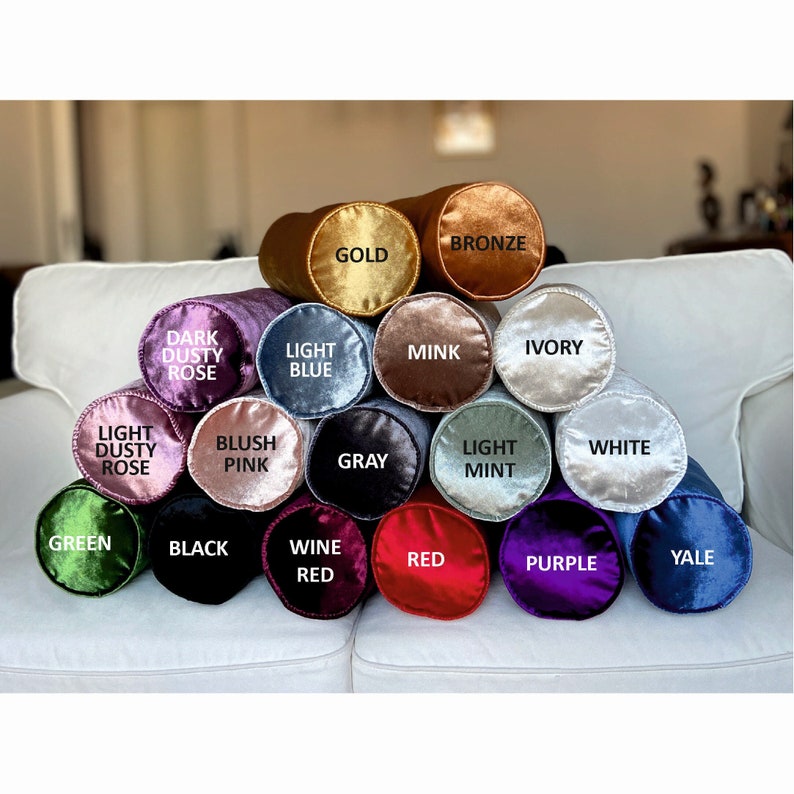K&ouml;nnte beinhalten: Eine Sammlung von 16 zylindrischen Kissen in verschiedenen Farben, darunter Gold, Bronze, Dunkelstaubrosa, Hellblau, Nerz, Elfenbein, Hellstaubrosa, Blush Pink, Grau, Hellmint, Wei&szlig;, Gr&uuml;n, Schwarz, Weinrot, Rot, Lila und Yale.